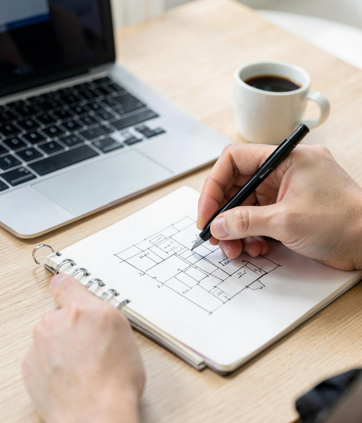 Schets van een websiteontwerp naast een laptop